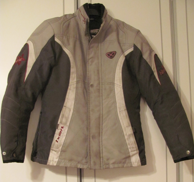 the ixon nirvana ladies motorcycle jacket in grey hung on a cupboard